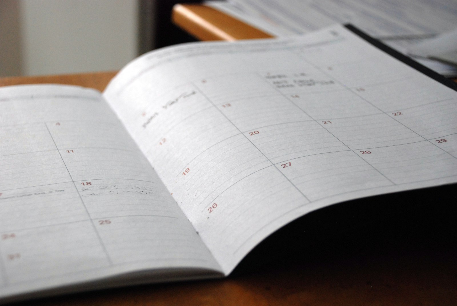 Open paper planner on a wood desk with a pen, ready for weekly planning