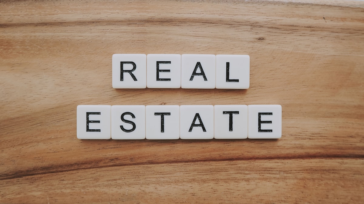 Real estate agent reviewing property listings on a laptop at a modern desk with market data on screen